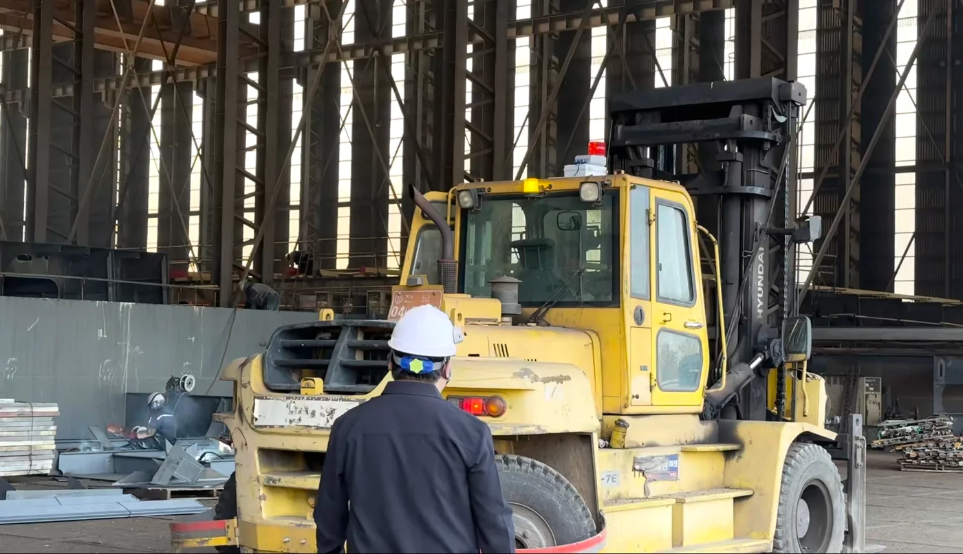 안전모에 UWB 태그를 단 작업자 앞에 경광등 수신기를 설치한 조선소 지게차